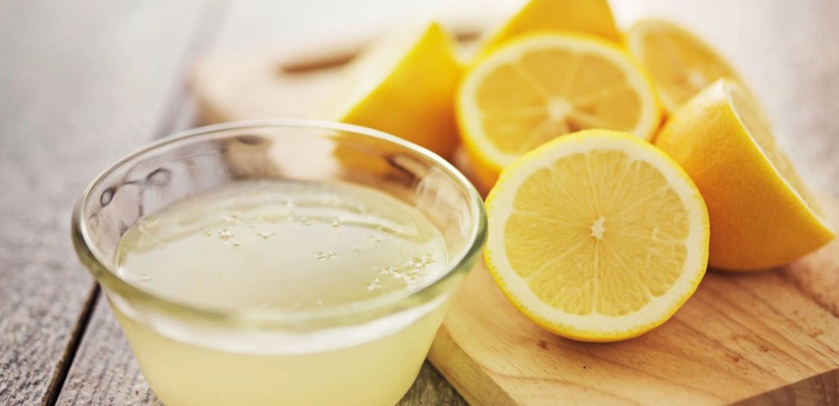 Bir bardak ılık limonlu su ve yanında dilimlenmiş taze limonlar
